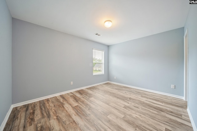 spare room featuring baseboards, visible vents, and light wood-style floors