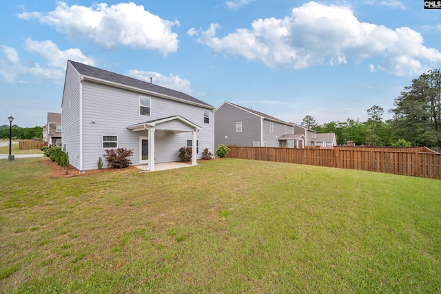 back of house featuring fence, a patio area, and a lawn