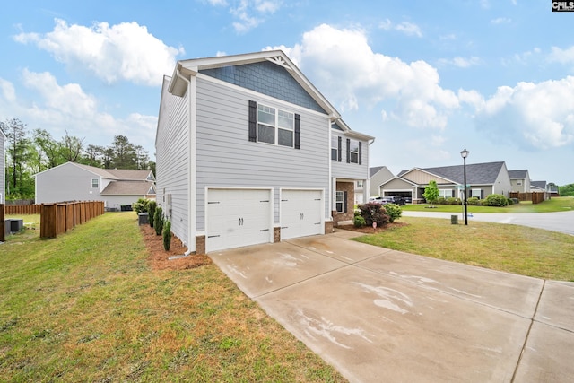 exterior space with fence, driveway, a yard, and an attached garage