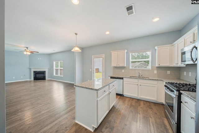 kitchen with tasteful backsplash, appliances with stainless steel finishes, a kitchen island, a sink, and visible vents