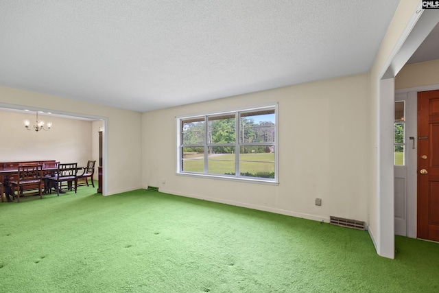 unfurnished living room featuring baseboards, a notable chandelier, a textured ceiling, and carpet flooring