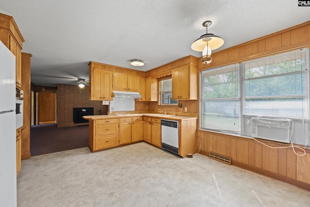 kitchen featuring wall oven, light countertops, white dishwasher, under cabinet range hood, and wooden walls