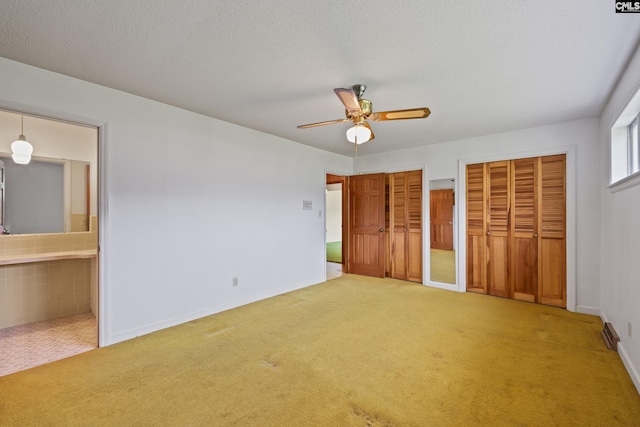 unfurnished bedroom with carpet, baseboards, multiple closets, and ensuite bathroom