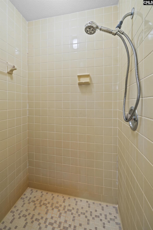 full bath with a tile shower and a textured ceiling