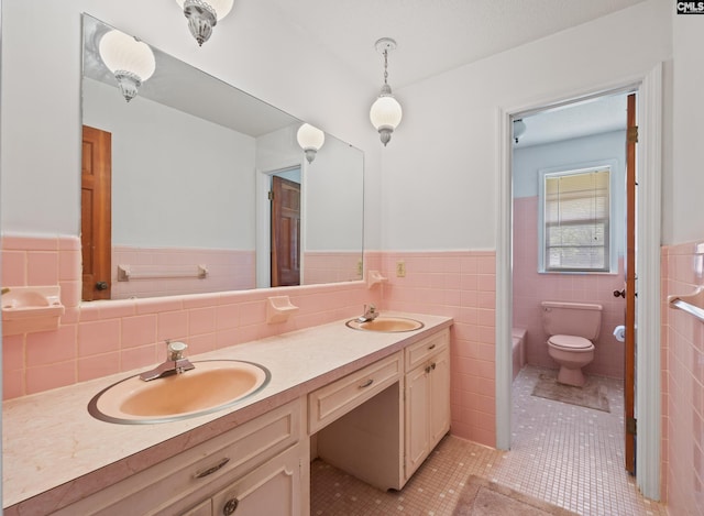 full bath featuring toilet, a wainscoted wall, tile patterned flooring, and a sink
