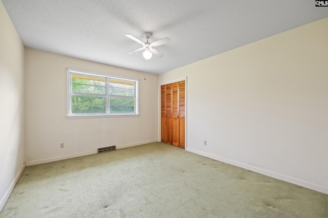 empty room with a textured ceiling, ceiling fan, visible vents, baseboards, and carpet floors