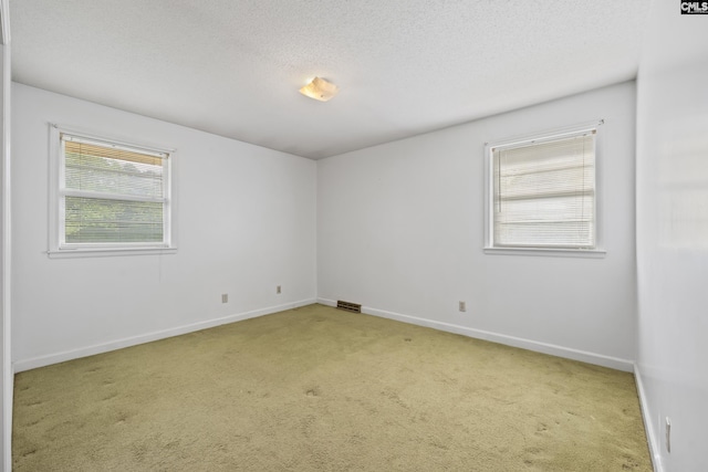 carpeted spare room with a textured ceiling, visible vents, and baseboards