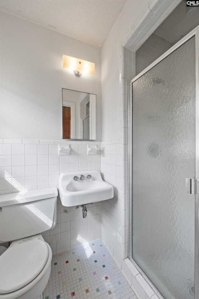 bathroom featuring tile walls, tile patterned floors, toilet, and a stall shower