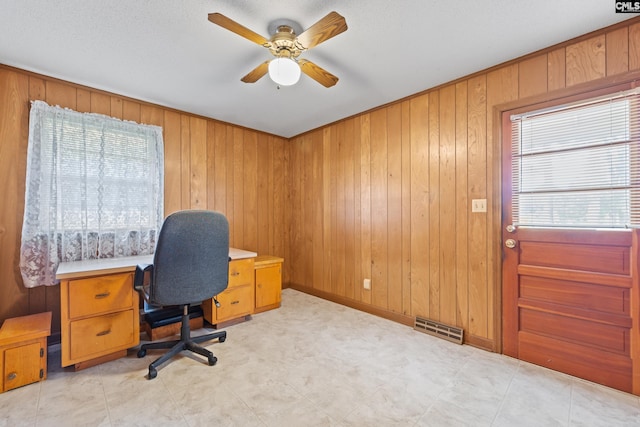 office featuring wood walls, ceiling fan, and visible vents