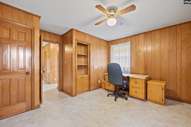 office space featuring wood walls, a textured ceiling, ceiling fan, and baseboards