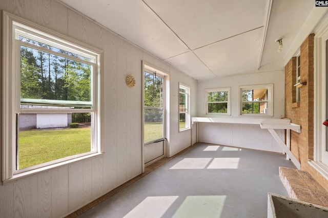 unfurnished sunroom featuring concrete flooring and wood walls