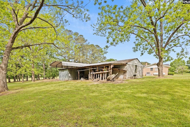 back of house featuring a carport, a yard, an outbuilding, and a pole building