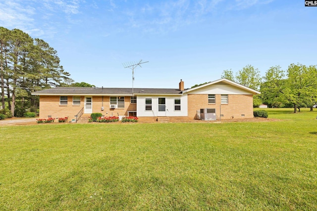 rear view of property with a lawn, a chimney, entry steps, and brick siding