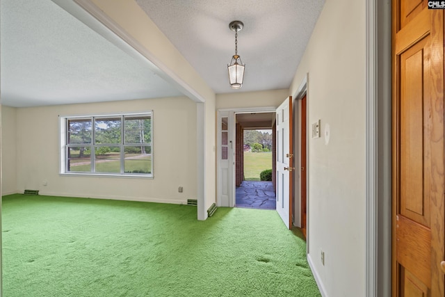carpeted entrance foyer featuring baseboards, visible vents, and a textured ceiling
