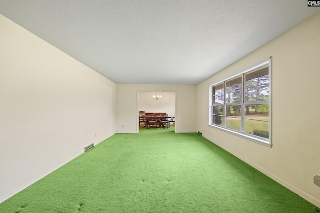 carpeted empty room featuring visible vents, a notable chandelier, a textured ceiling, and baseboards