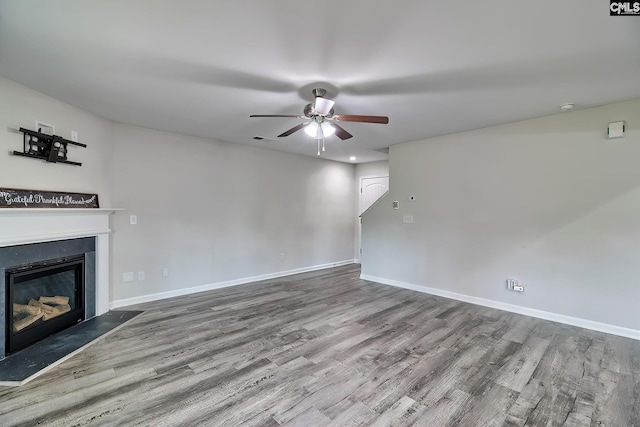 unfurnished living room featuring visible vents, wood finished floors, ceiling fan, and a glass covered fireplace