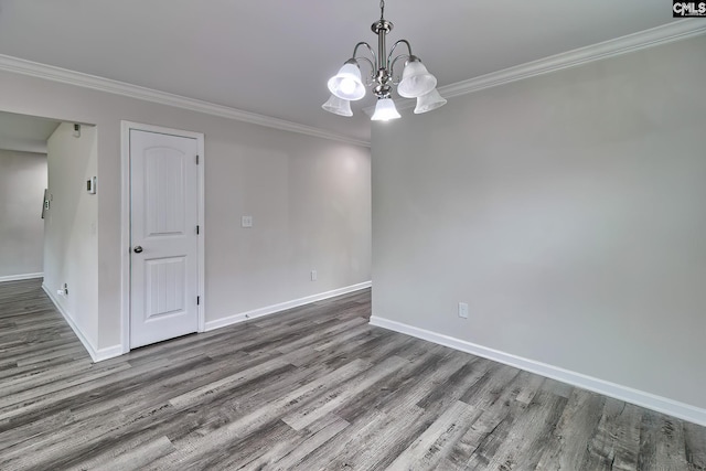 spare room featuring baseboards, wood finished floors, and a notable chandelier