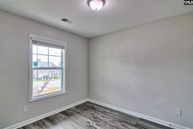 spare room featuring dark wood-type flooring, visible vents, and baseboards