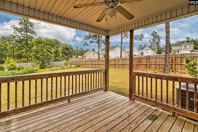 wooden terrace with a fenced backyard, a ceiling fan, a yard, and a residential view