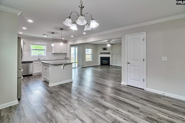 kitchen featuring stainless steel dishwasher, a sink, open floor plan, ornamental molding, and a fireplace