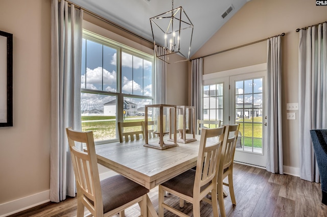 dining area featuring lofted ceiling, visible vents, baseboards, wood finished floors, and a notable chandelier