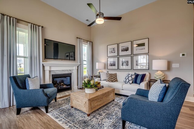 living area with wood finished floors, a high end fireplace, baseboards, a ceiling fan, and lofted ceiling