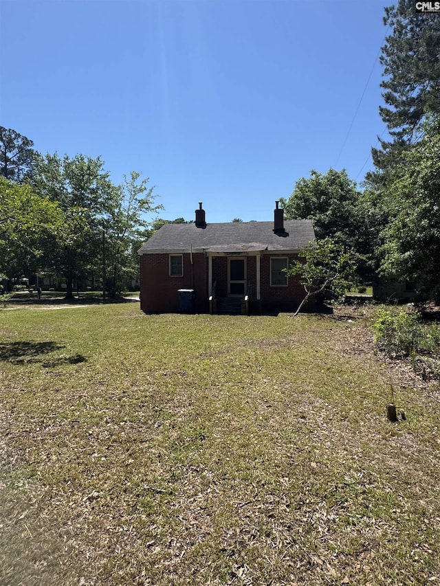 back of property featuring a lawn and a chimney