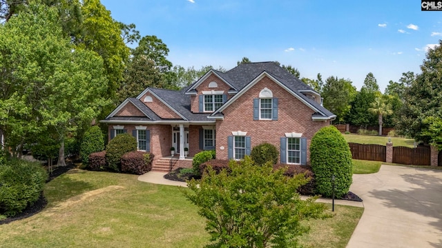 view of front of property with brick siding, fence, and a front yard