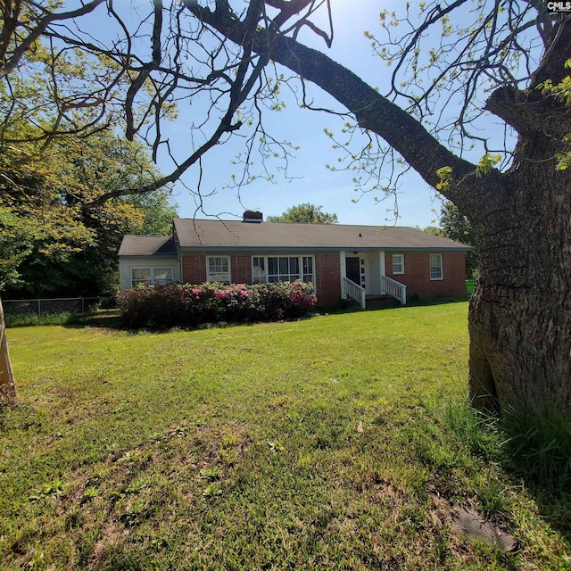 ranch-style home featuring a front lawn, brick siding, and fence