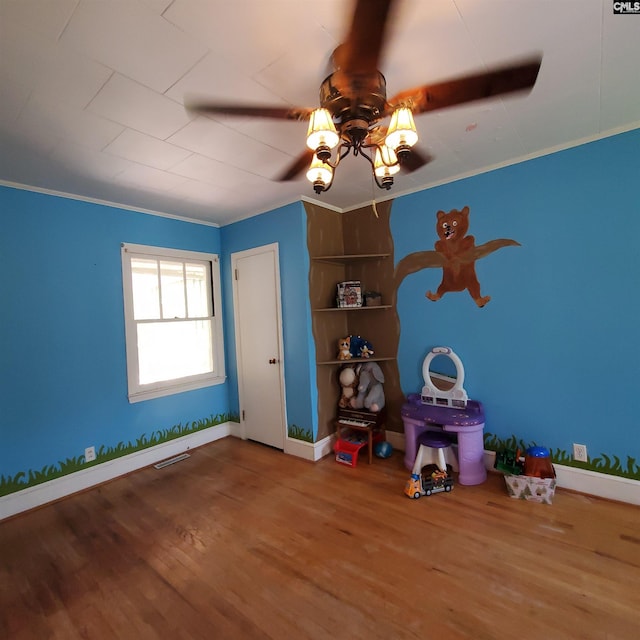 unfurnished bedroom featuring baseboards, visible vents, wood finished floors, and crown molding