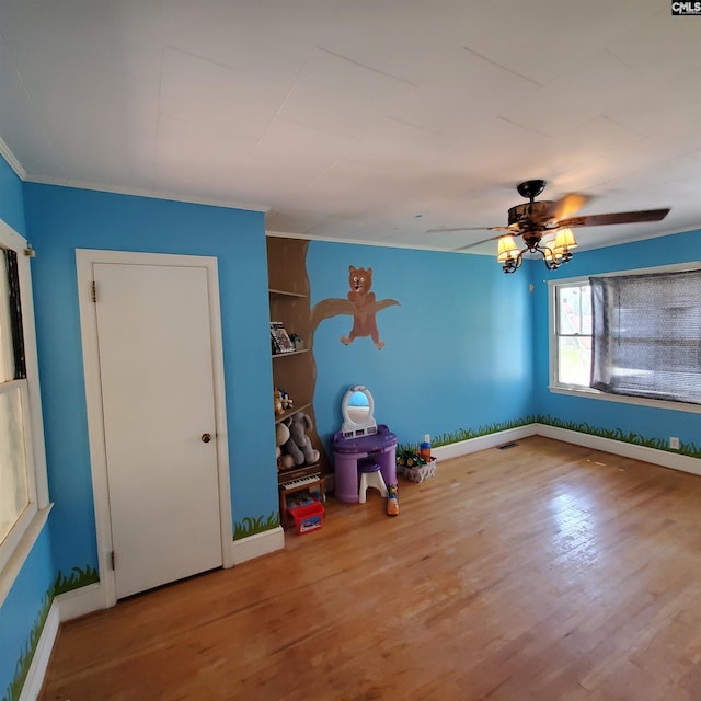 rec room featuring wood finished floors, a ceiling fan, ornamental molding, and baseboards