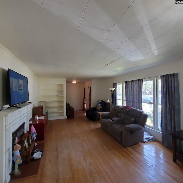 living room with built in features, wood finished floors, and a fireplace