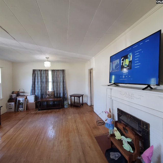 living room with wood finished floors, crown molding, and a fireplace