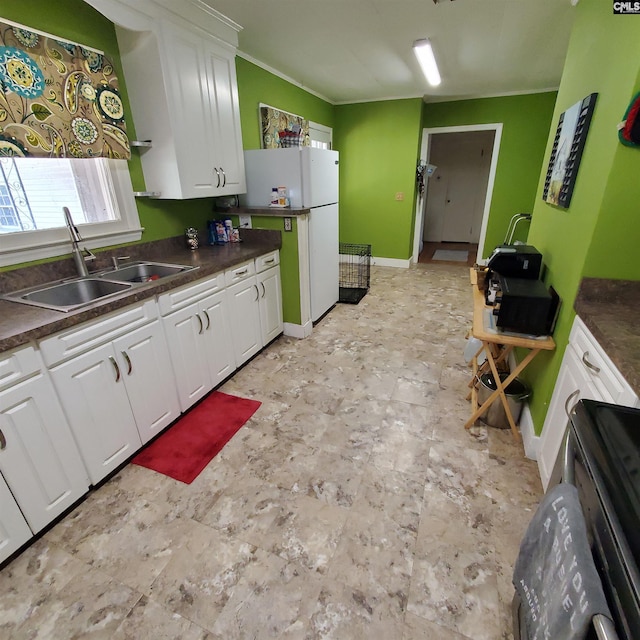 kitchen featuring a sink, crown molding, white cabinetry, dark countertops, and freestanding refrigerator