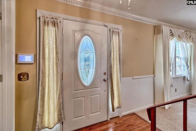 entrance foyer with wood finished floors, a healthy amount of sunlight, ornamental molding, and baseboards