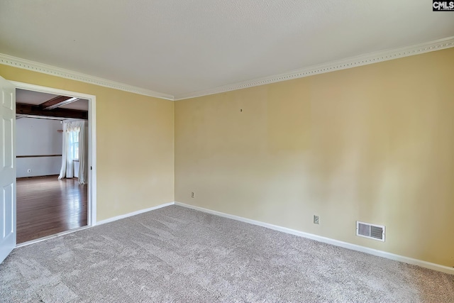 empty room featuring baseboards, visible vents, carpet, and crown molding