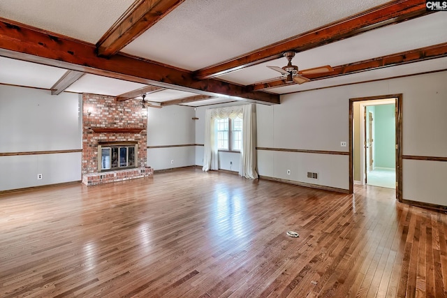unfurnished living room featuring beam ceiling, hardwood / wood-style flooring, a ceiling fan, and baseboards