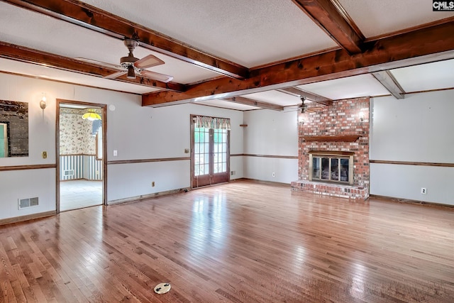unfurnished living room with a ceiling fan, visible vents, hardwood / wood-style flooring, and a fireplace