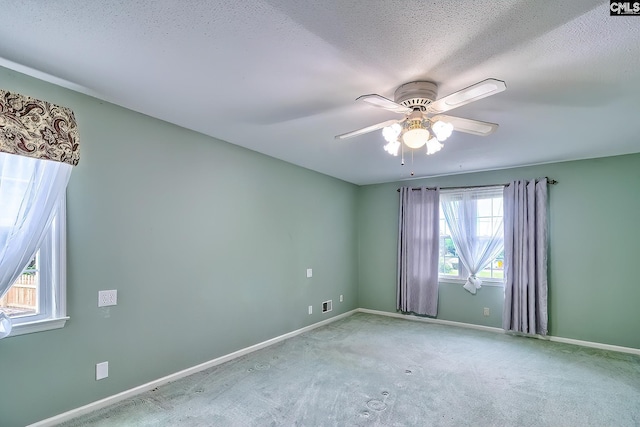 empty room with baseboards, a ceiling fan, carpet floors, and a textured ceiling