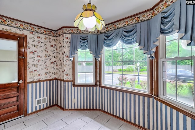 unfurnished dining area featuring a wealth of natural light, visible vents, and wallpapered walls