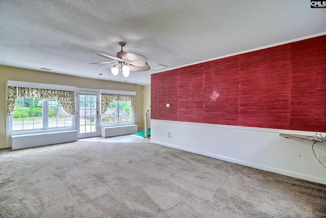 empty room featuring a textured ceiling, ceiling fan, visible vents, baseboards, and carpet