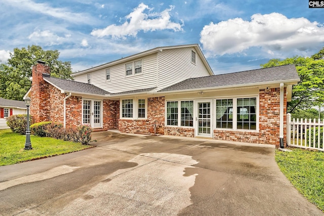 rear view of property with a chimney, a patio area, fence, french doors, and brick siding