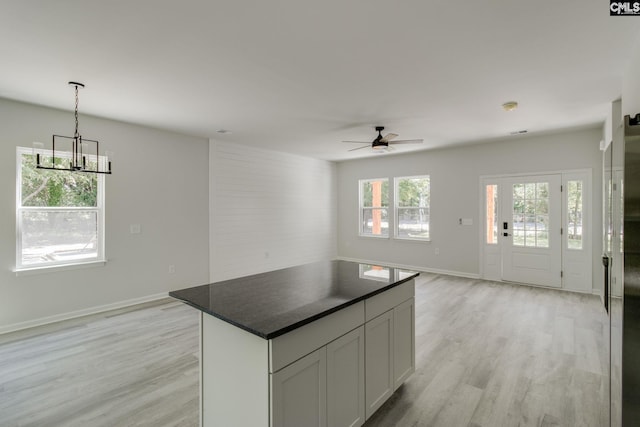 kitchen featuring dark countertops, ceiling fan with notable chandelier, open floor plan, and light wood-style floors