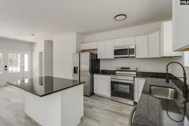 kitchen featuring stainless steel appliances, light wood-type flooring, white cabinets, and a sink