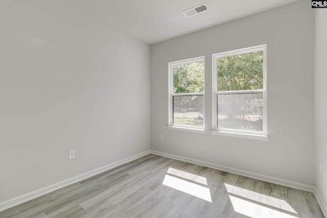 unfurnished room featuring baseboards, visible vents, and light wood finished floors
