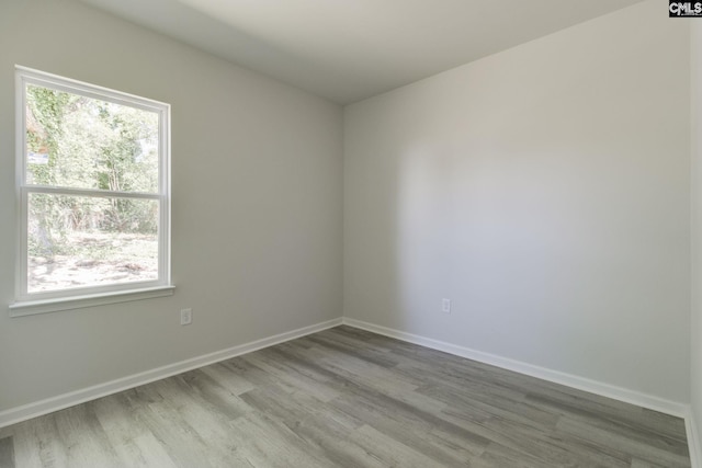 spare room with baseboards, wood finished floors, and a healthy amount of sunlight