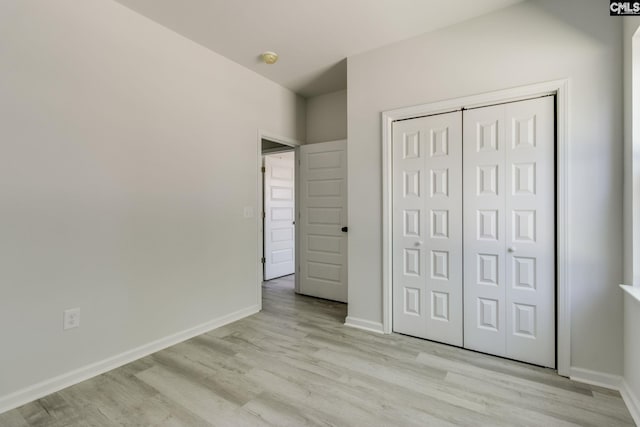 unfurnished bedroom featuring baseboards, a closet, and light wood-style flooring
