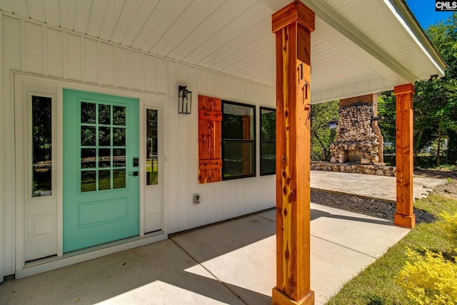 property entrance with an outdoor stone fireplace and board and batten siding