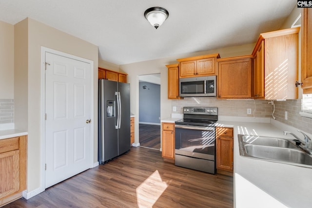kitchen with tasteful backsplash, a sink, stainless steel appliances, light countertops, and dark wood-style floors