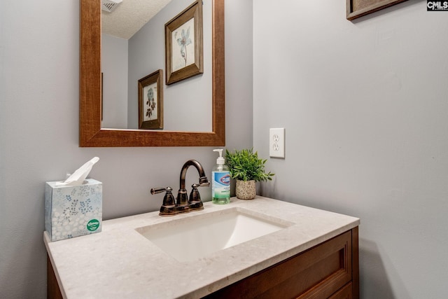 bathroom featuring a textured ceiling, visible vents, and vanity